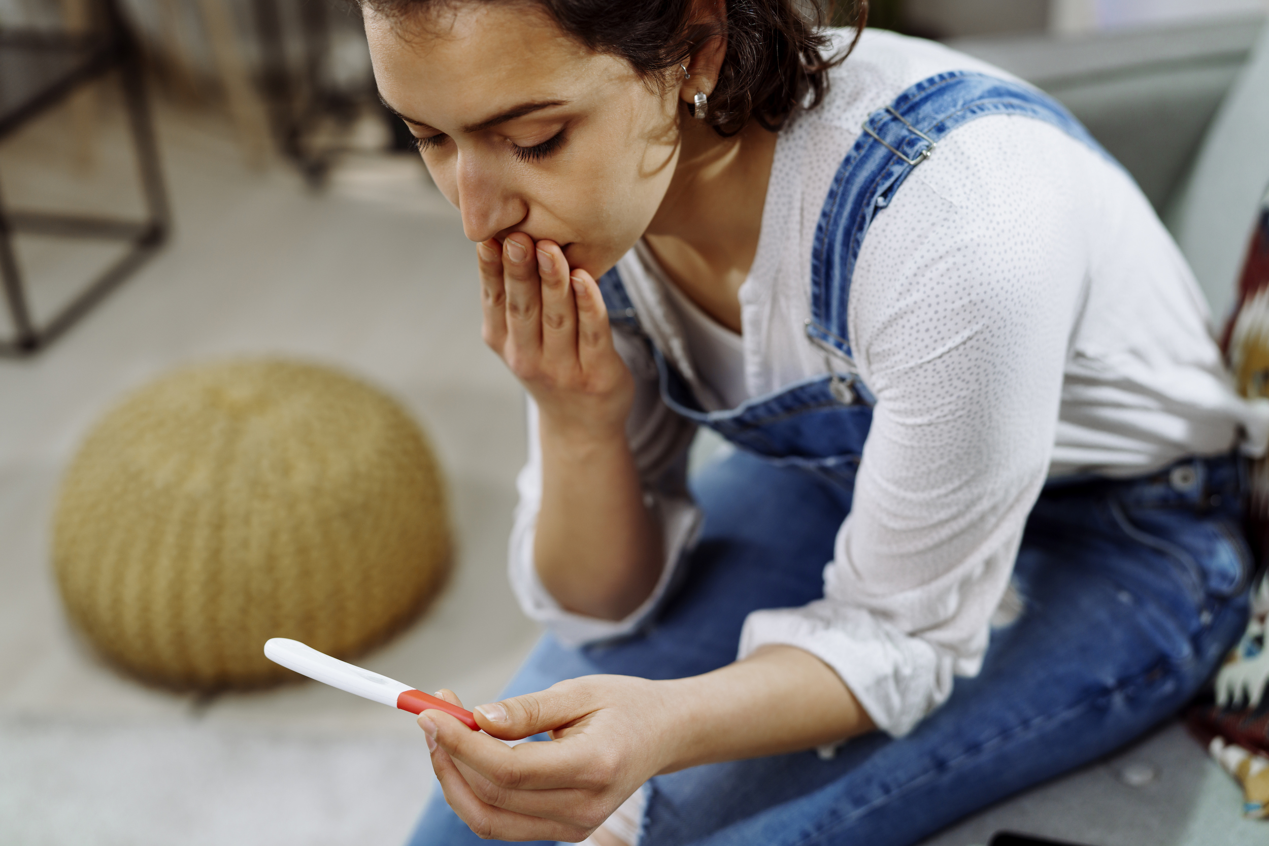 Worried woman holding pregnancy test